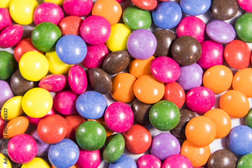 Background of the colorful button shaped candies filled with chocolate Background of the colorful button shaped candies filled with chocolate