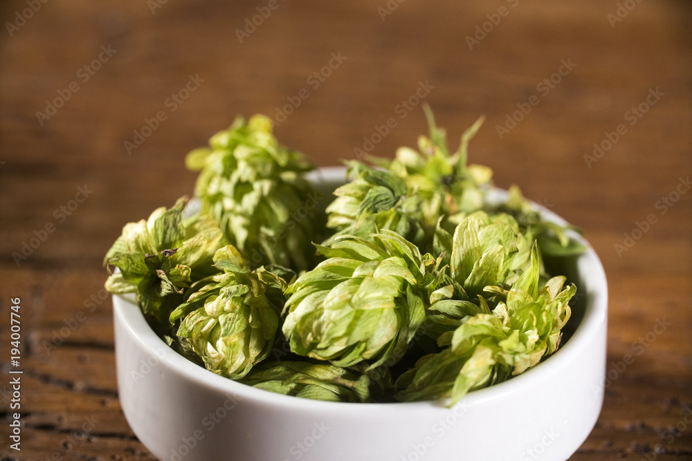Beer brewing ingredients Hop cones in wooden bowl and wheat ears on wooden background. Beer brewery concept. Beer brewing ingredients Hop cones in wooden bowl and wheat ears on wooden background. Beer brewery concept.