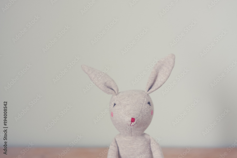 Cute toy bunny close up with natural background. Single object, light beige. Shallow depth of field. Easter bunny. Minimalistic. Matte vintage filter.