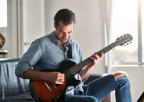 smiling handsome man having fun playing guitar