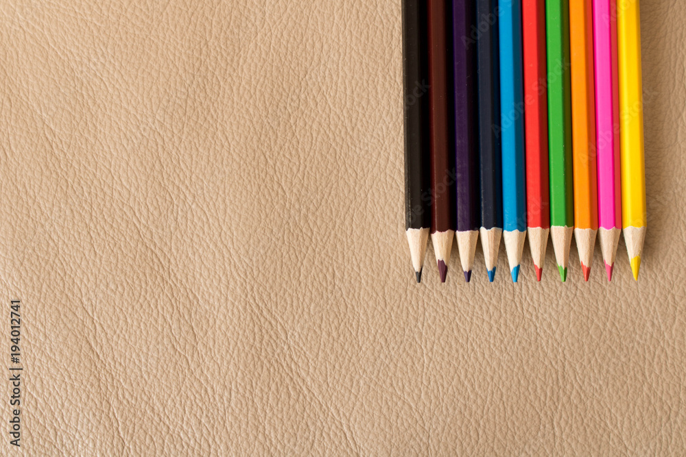 Obraz premium A set of colored pencils on a leather sofa . Beige background