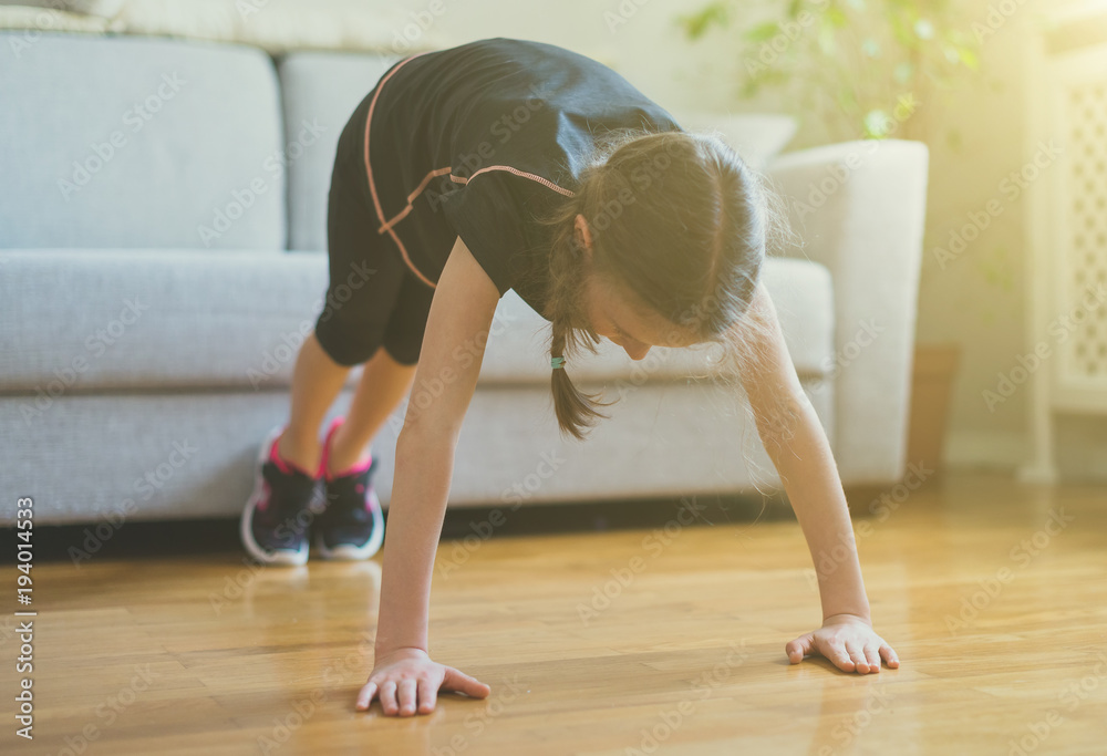 Little girl doing push ups at home. Gymnastics at home. Little girl doing push ups at home. Gymnastics at home.