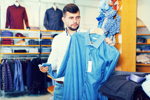 man customer looking classic shirt in fashion store