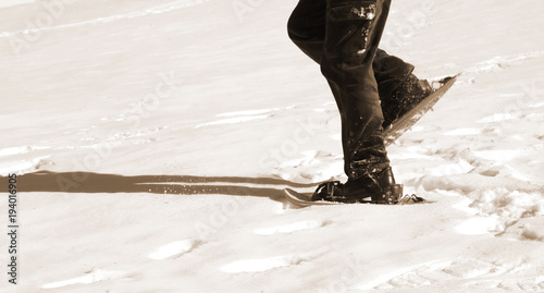 man walks with snowshoes on snow with sepia effect photo