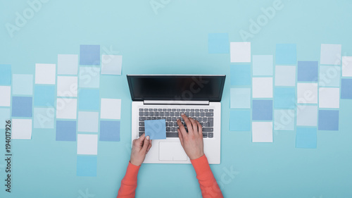 Woman working with a laptop and sticky notes