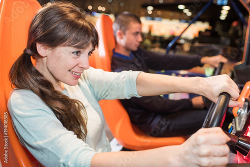 young pretty woman having fun in car simulator photo