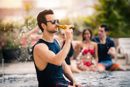 Handsome Man Drinking Beer in the Pool Party in an Evening - Recreation and Lifestyle Concept