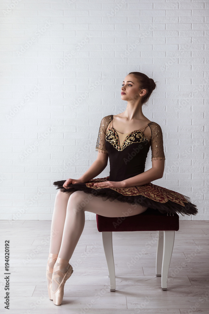 Obraz premium Portrait of Young Beautiful perfect ballerina sitting on chair indoors