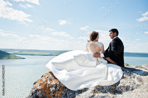 Wedding couple at breathtaking landscape with rock and lake. © AS Photo Family