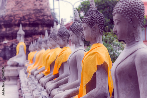 Close up of Ancient Buddha Statue in a row with a yellow fabric at WAT YAI CHAI MONGKOL, The Historic City of Ayutthaya, Thailand photo