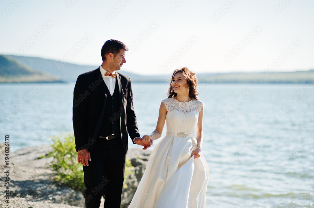 Wedding couple at breathtaking landscape with rock and lake. Wedding couple at breathtaking landscape with rock and lake.