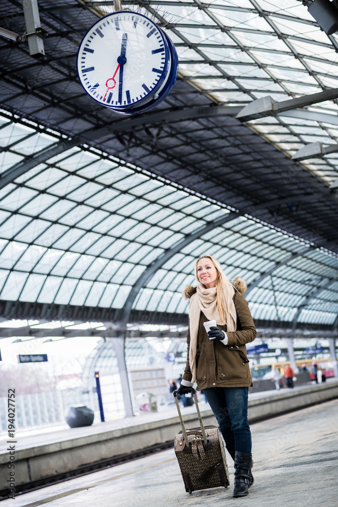 Frau mit Gepäck läuft am Bahnsteig auf Bahnhof entlang