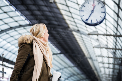 Quadro su tela Frau schaut auf Uhr im Bahnhof weil ihr Zug Verspätung hat
