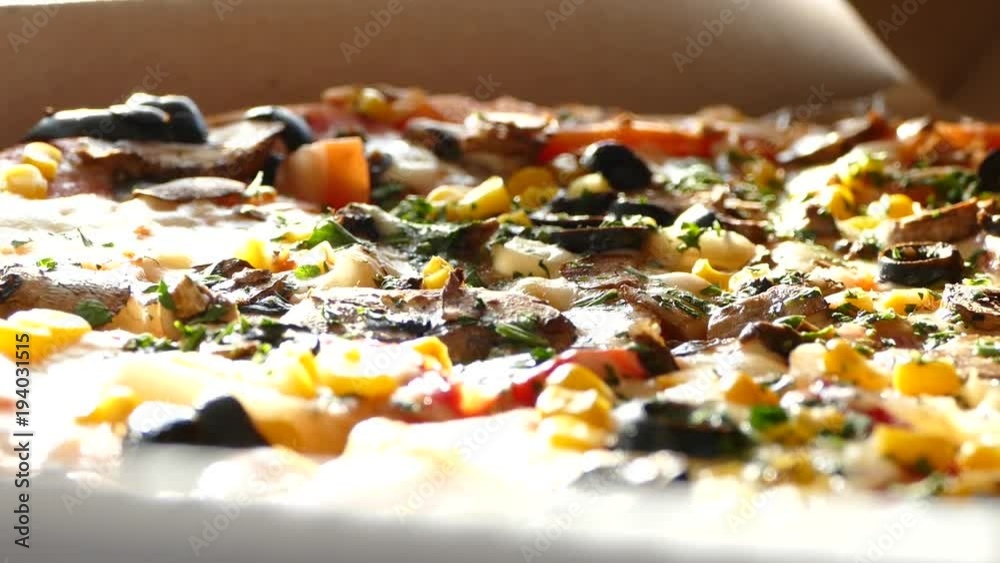 Delivery of pizza in a box. A delicious juicy and beautiful pizza is cut with a round knife. The family eats pizza with mushrooms, olives, cheese and tomatoes. Delivery of pizza in a box. A delicious juicy and beautiful pizza is cut with a round knife. The family eats pizza with mushrooms, olives, cheese and tomatoes.