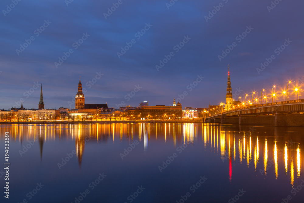 Skyline of old town of Riga seen across the river Daugava with the stone bridge at night.