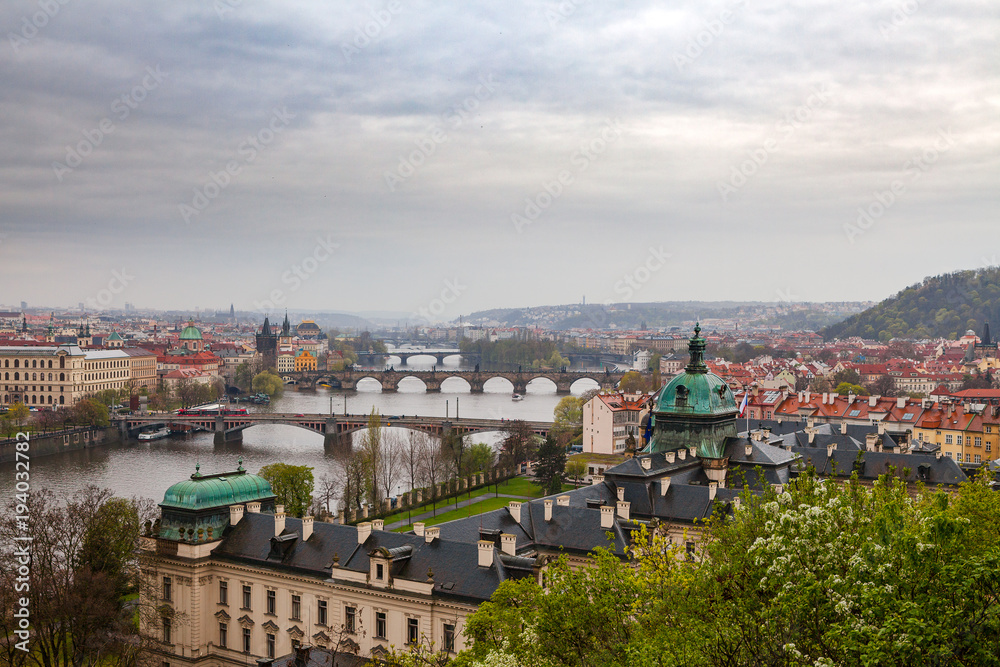 Prague view with a river and bridges from hill with park Letensky garden. Gloomy weather.
