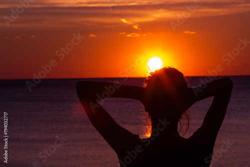 Silhouette of a girl while enjoying ocean scenery in sunset / sunrise time.