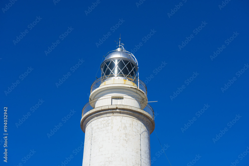 Mallorca, lighthouse next to the Mediterranean Sea, blue sky without clouds with calm waters. serves to warn ships of the presence of rocks Mallorca, lighthouse next to the Mediterranean Sea, blue sky without clouds with calm waters. serves to warn ships of the presence of rocks