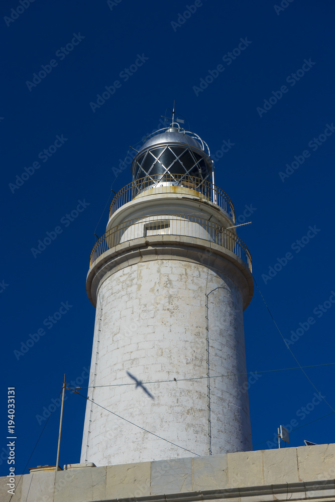 lighthouse next to the Mediterranean Sea, blue sky without clouds with calm waters. serves to warn ships of the presence of rocks