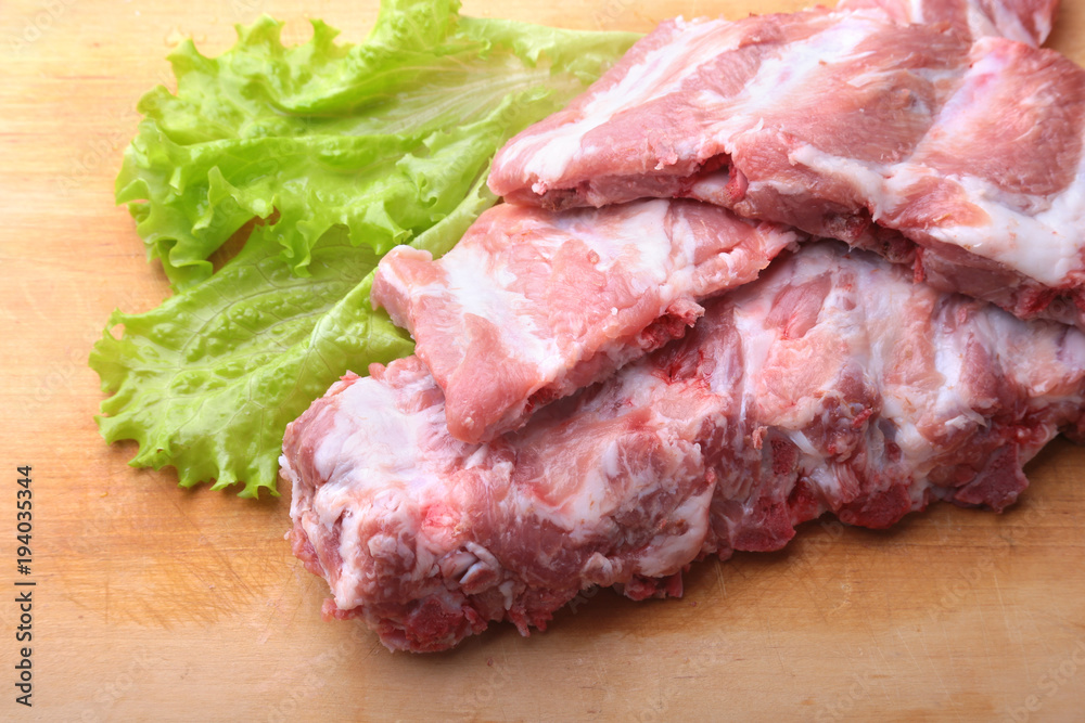 Raw Ribs on a rustic cutting board with salt, pepper and grinder for spices . copy space. Top View.