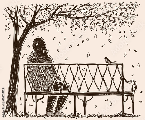 A lonely girl sits o a bench in an autumn park