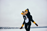 Young couple in the penguin costumes are have fun on snow. Happy Loving Couple