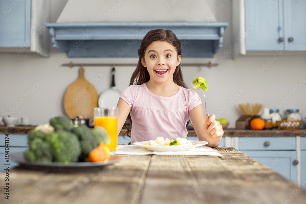 Yummy. Pretty pleased dark-haired little girl smiling and having healthy breakfast and drinking some juice Yummy. Pretty pleased dark-haired little girl smiling and having healthy breakfast and drinking some juice
