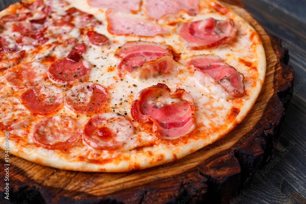 Hot fresh pizza with bacon, salami,ham and pepperoni, close up. Italian food, restaurant or pizzeria concept Hot fresh pizza with bacon, salami,ham and pepperoni, close up. Italian food, restaurant or pizzeria concept