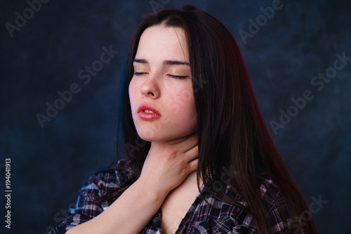 Young sick woman suffering from a sore throat and painful swallowing. Girl touching her neck by hands. Illness, pharmacy and medicine concept