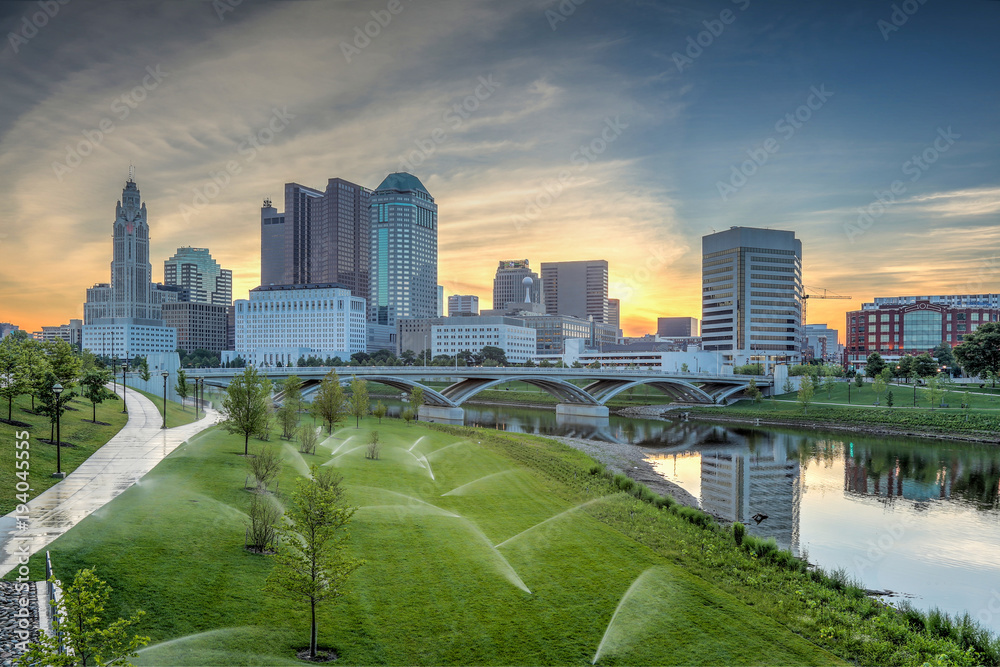 Skyline along the Scioto River showcasing the Leveque Tower and Supreme Court building with sprinklers activated.  - obrazy, fototapety, plakaty 