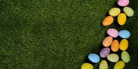 above top view of multi colored painted easter egg on springtime grown green grass