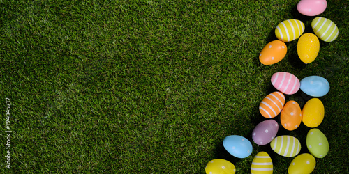 above top view of multi colored painted easter egg on springtime grown green grass