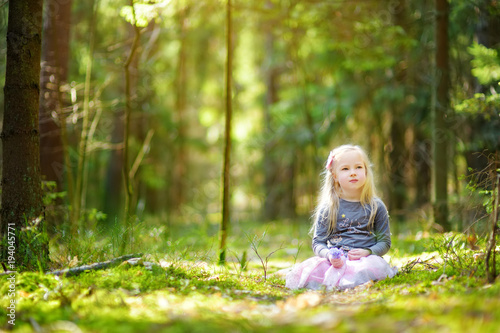 Adorable little girl picking the first flowers of spring in the woods on beautiful sunny spring day © MNStudio