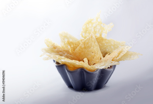 crisp parmesan cheese chips, finger food party snack or appetizer in a bowl on a light gray background, copy space