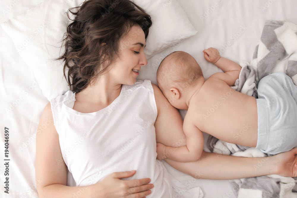 Young mother and her baby lying on bed at home