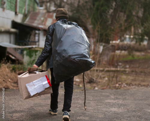 Poor man with packages of garbage outdoors