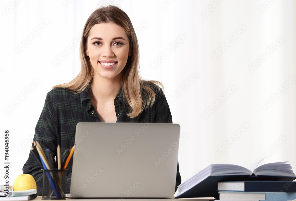 Pretty student with laptop studying at table indoors Pretty student with laptop studying at table indoors