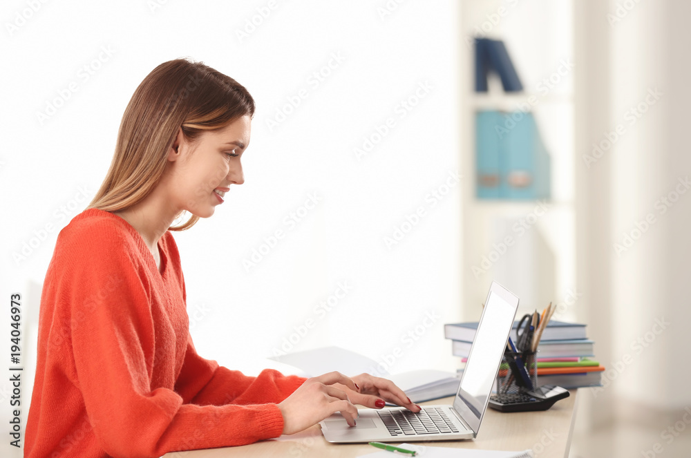 Fototapeta premium Pretty student with laptop studying at table indoors