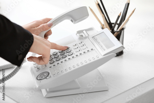 Woman using landline phone ...