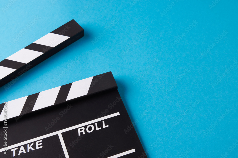 Movie clapper board on blue background with copy space, close-up, view from above. Cinema and movie time concept