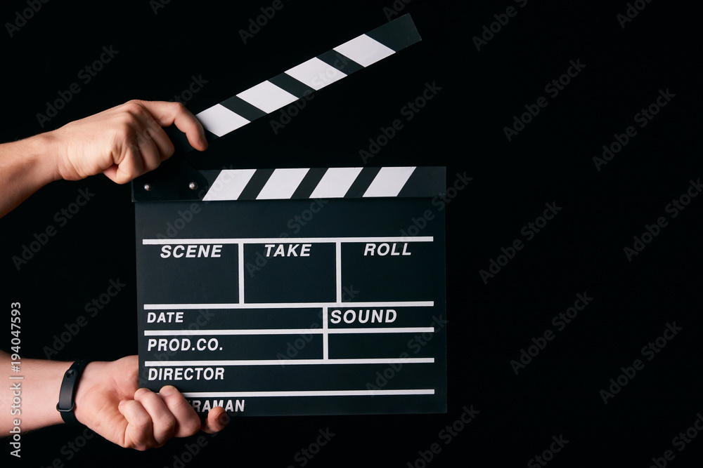 Hands with a movie clapperboard isolated on black background with copy space, close-up. Wooden clapper board as cinema and movie time concept