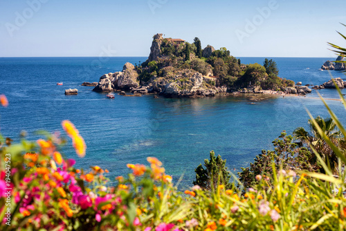 The Isola Bella island and beach with blurred flowers in the front in Taormina, Italy photo