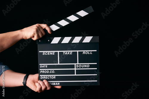 Fototapeta Hands with a movie clapperboard isolated on black background with copy space, close-up