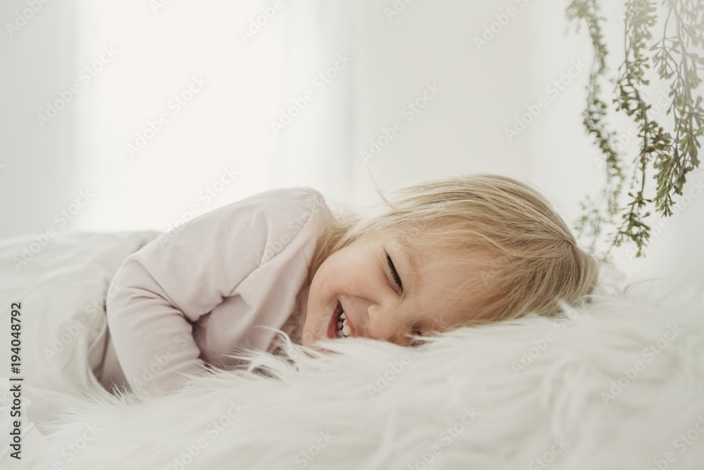 Cheerful girl lying on fur blanket at home Cheerful girl lying on fur blanket at home