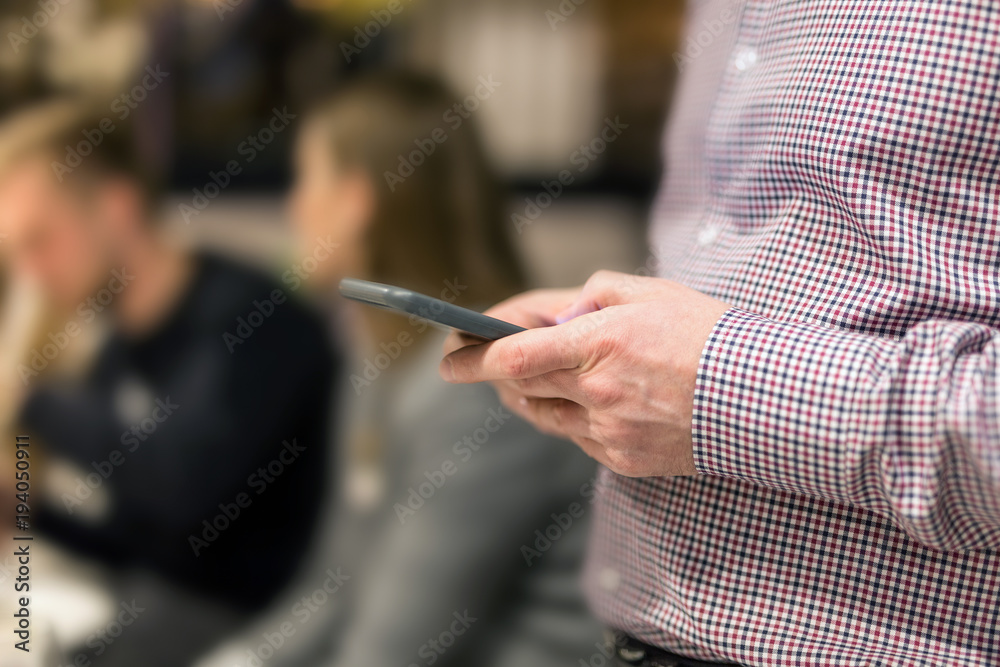 Man in shirt holding smartphone in hand. Businesman using phone during corporate meeting Man in shirt holding smartphone in hand. Businesman using phone during corporate meeting