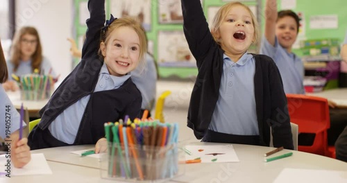 4K Happy enthusiastic young school children putting their hands up in class. Slow motion