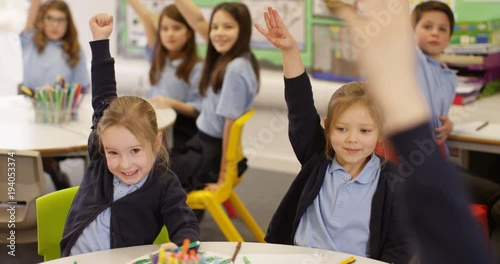 4K Happy enthusiastic young school children putting their hands up in class. Slow motion
