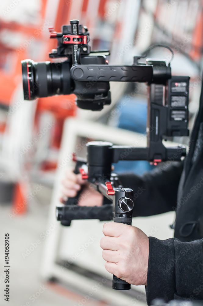 Videographer using stadicam, making video of machine at factory Videographer using stadicam, making video of machine at factory