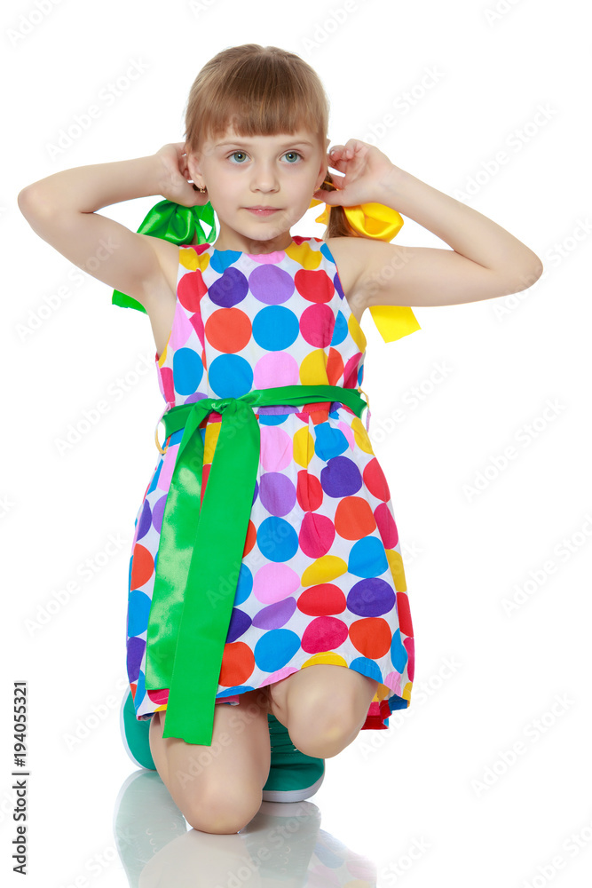 A little girl in a dress with a pattern from multi-colored circl A little girl in a dress with a pattern from multi-colored circl