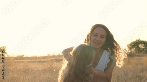 Family outdoors. Mother and daughter leisure together. The mother holds the little girl in her arms and turns around.